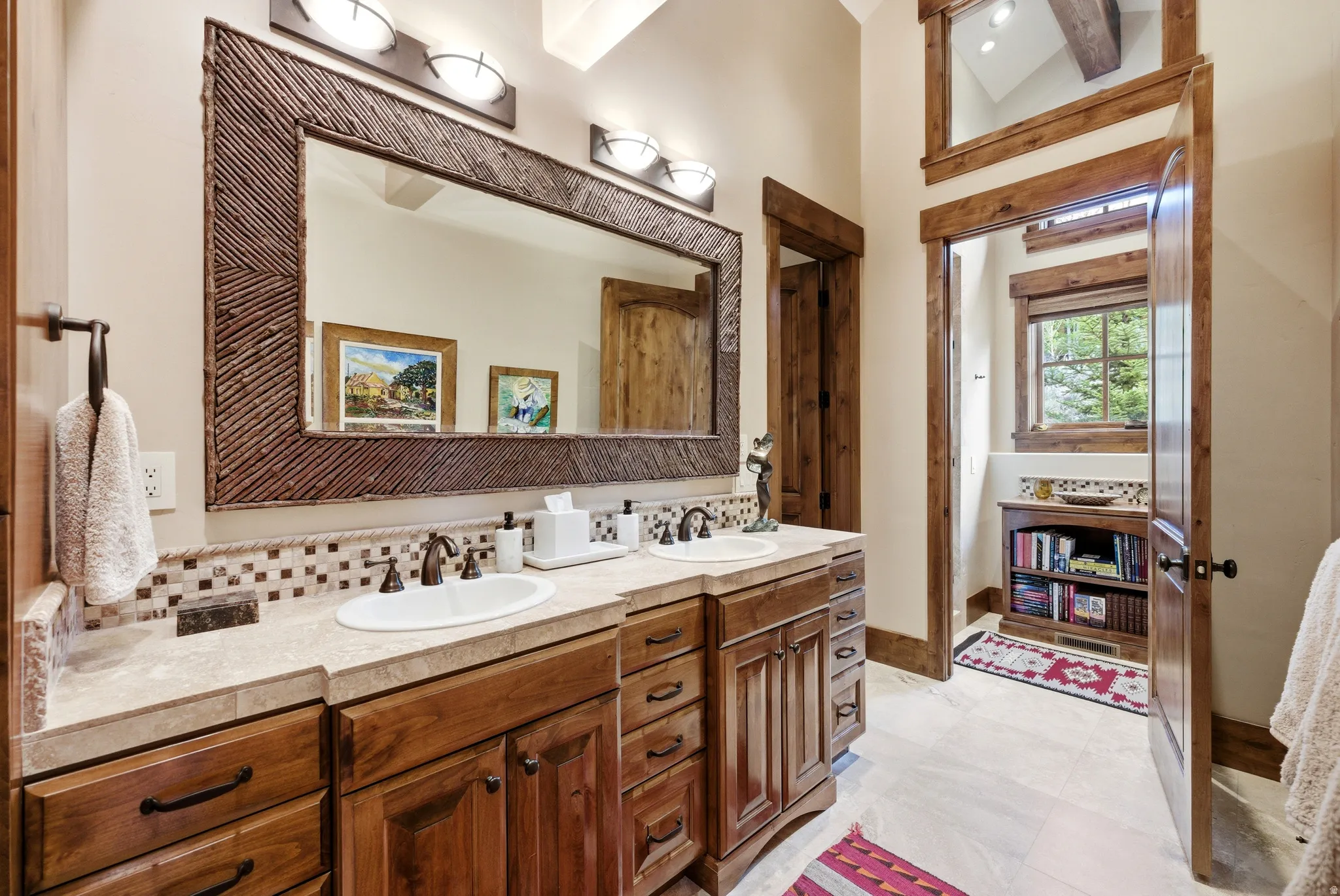 Double vanity featuring wood cabinetry with bronze hardware, dual undermount sinks, and a light-toned countertop