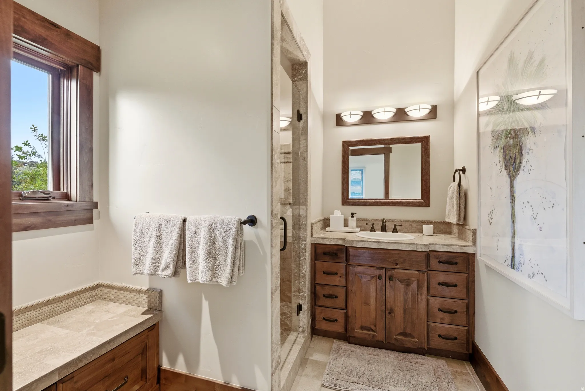 Bathroom featuring a wood vanity with integrated sink, stone countertop, and wood-framed mirror