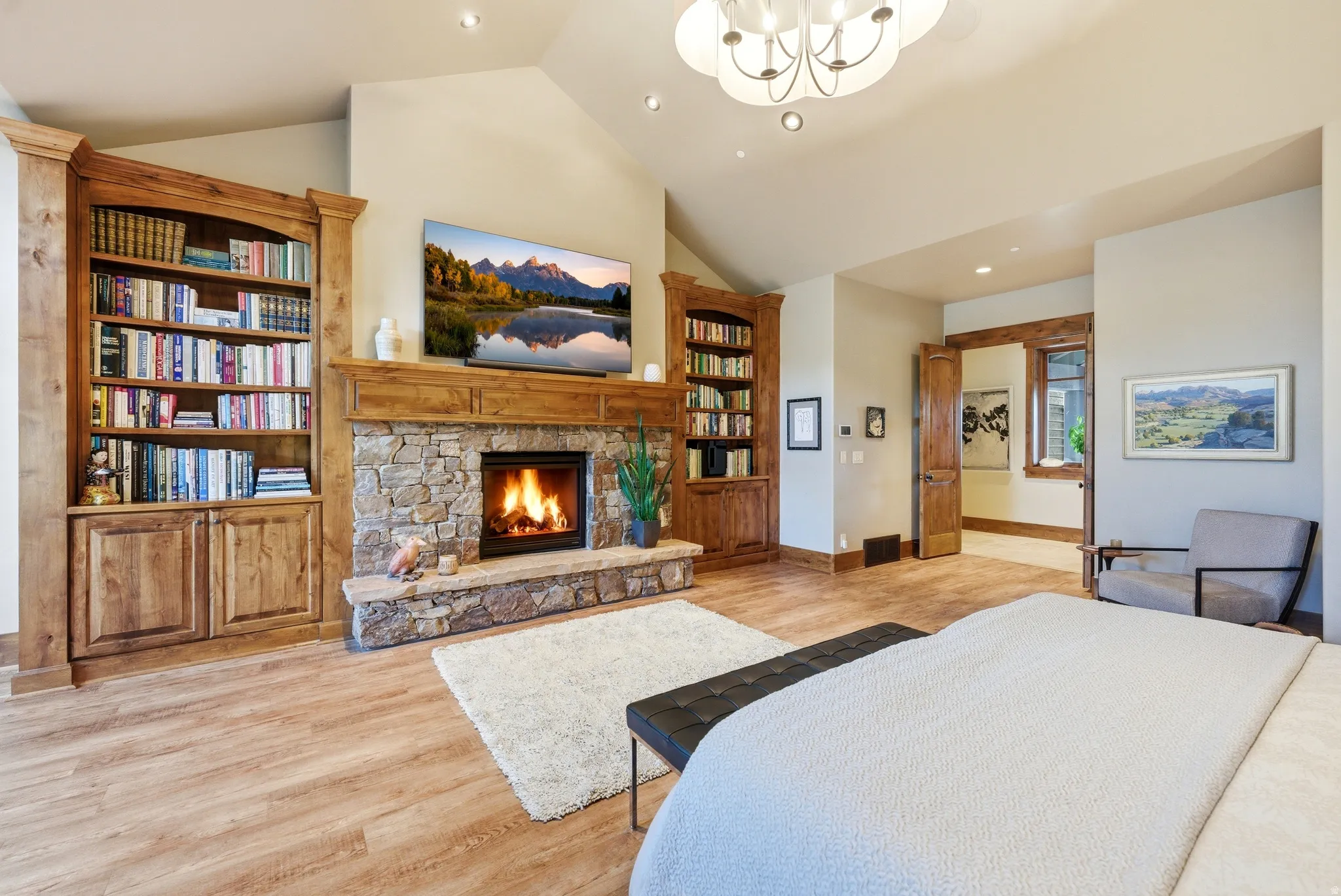 Stone fireplace with a wood-finish mantle, flanked by built-in bookcases, and wood-finish flooring underfoot