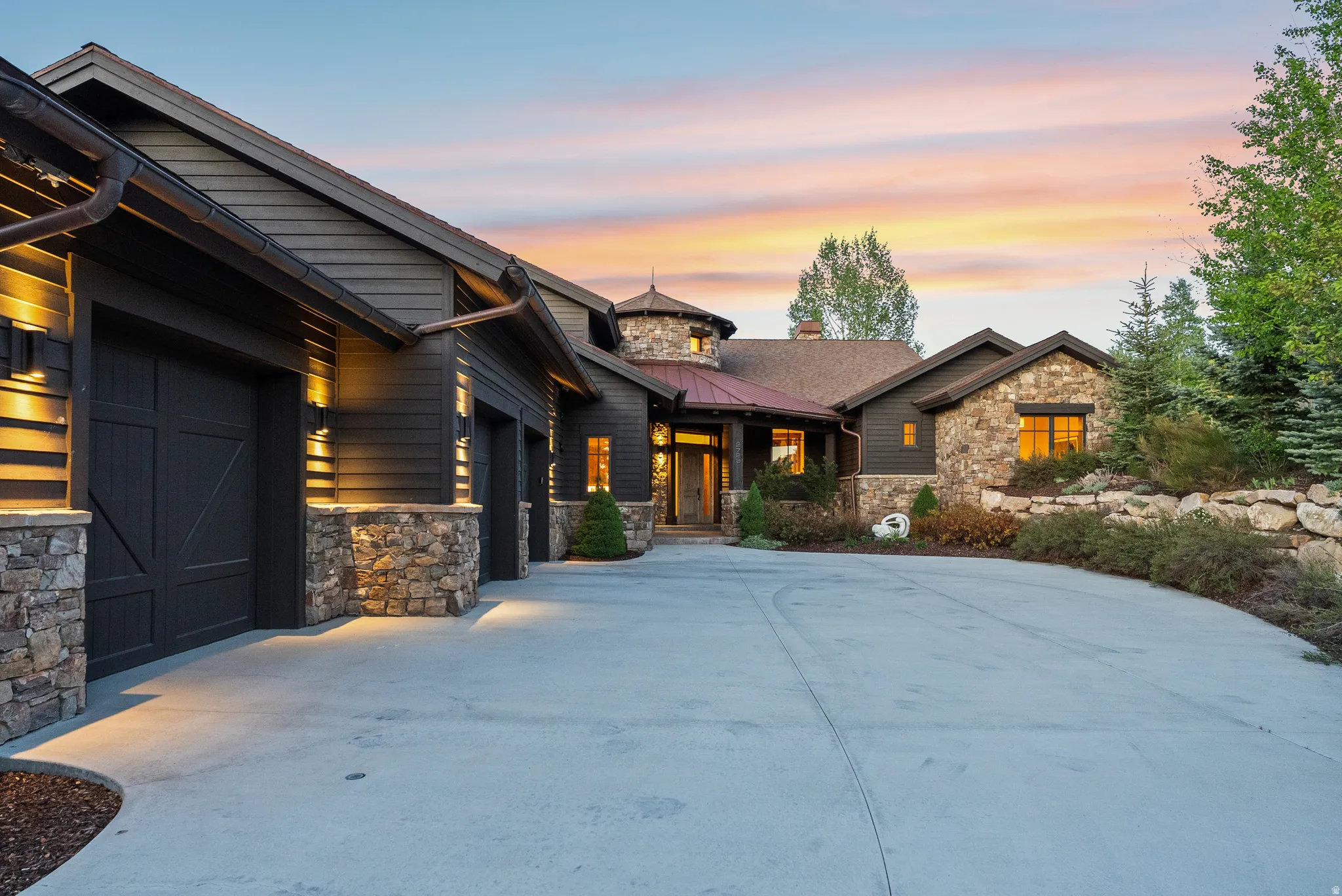 Expansive concrete driveway leading to a multi-car garage with carriage-style doors