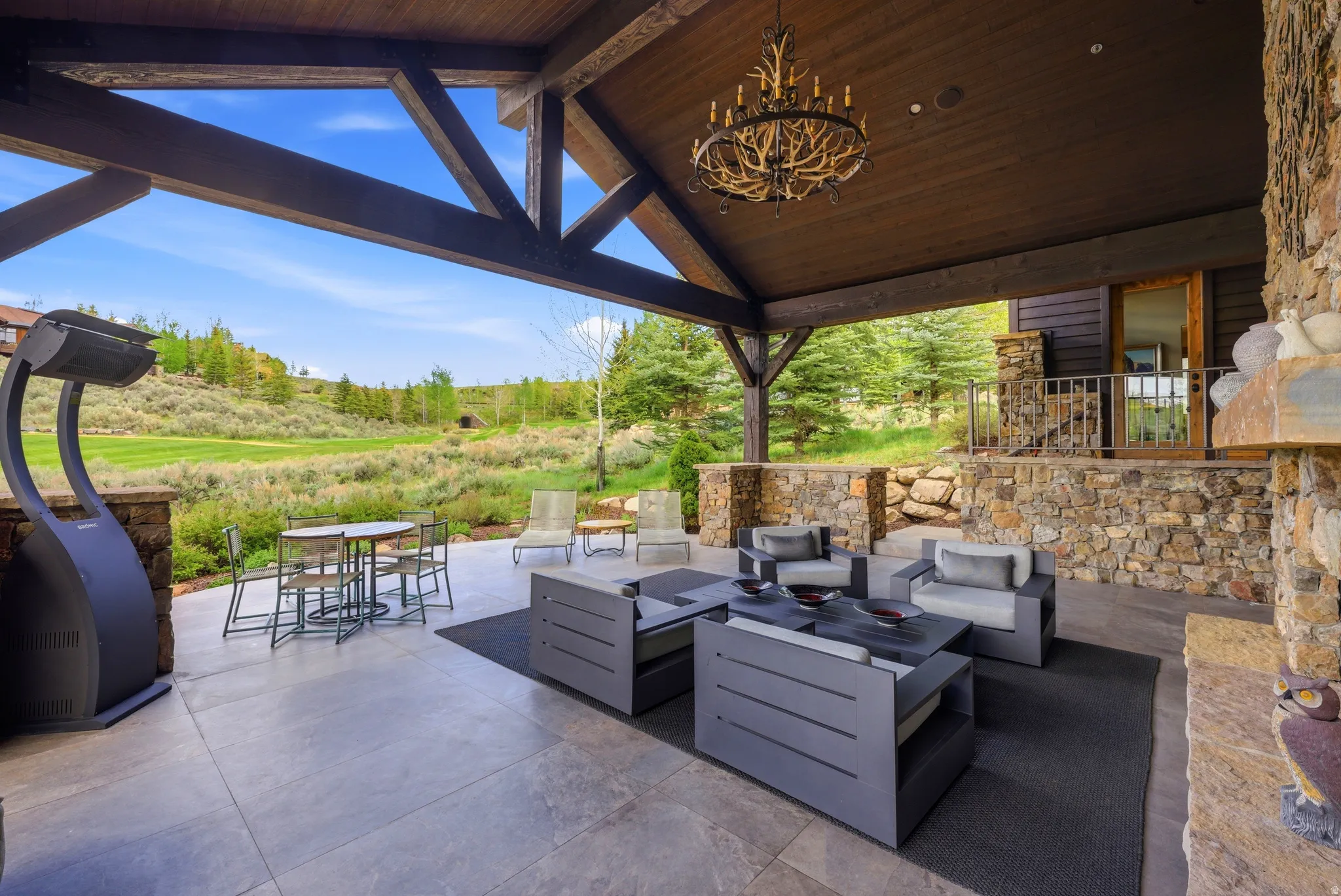 Covered outdoor patio featuring exposed wood beams and a stone fireplace