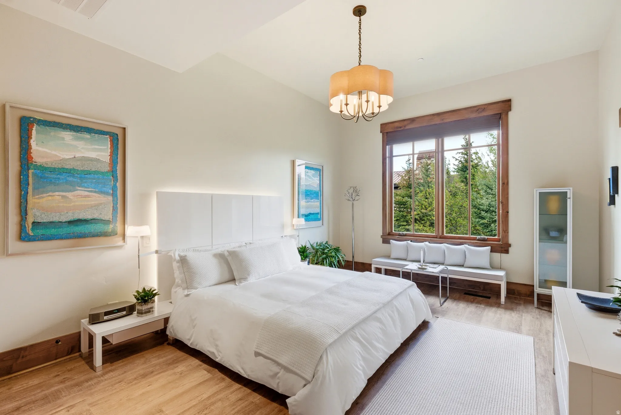Spacious room featuring wood-finish flooring, a vaulted ceiling, and a large window with wood trim