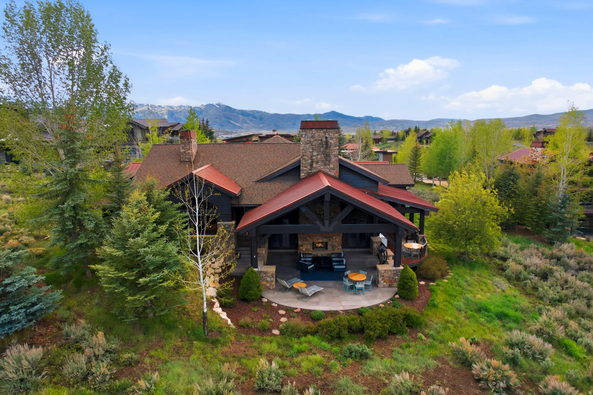 Mountain-style residence featuring a stone chimney and covered patio