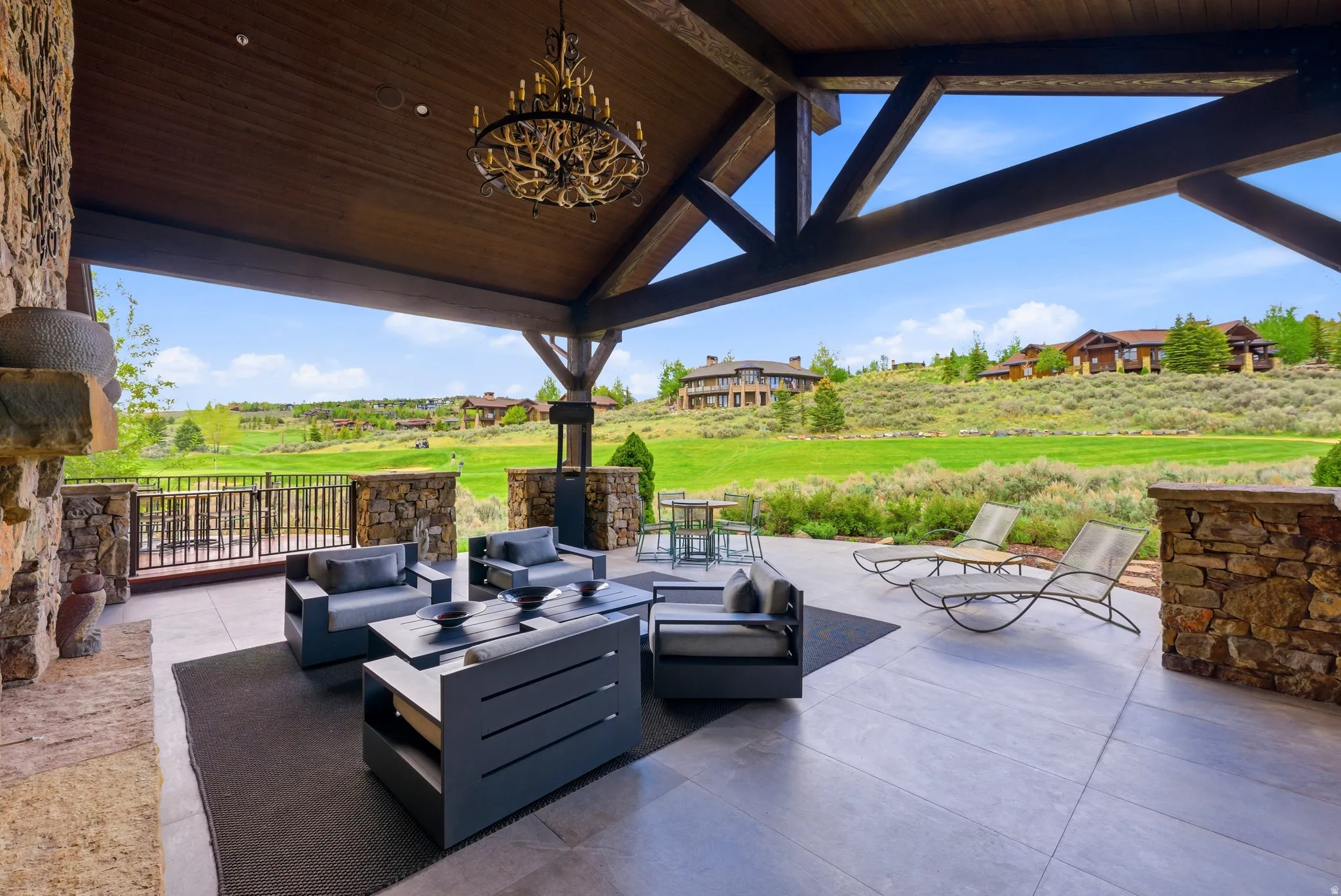 Covered outdoor living area featuring a stone-clad fireplace and wood-plank ceiling