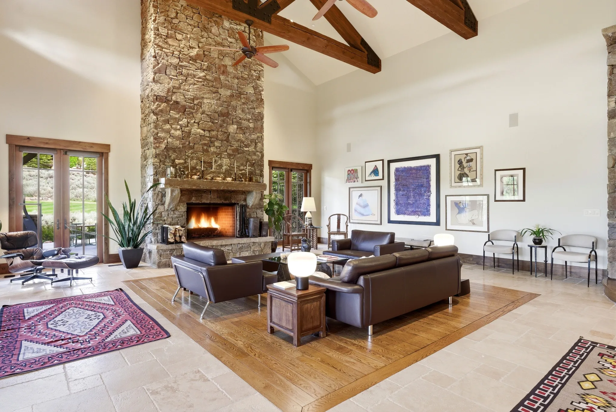 Great room featuring a floor-to-ceiling stone fireplace, vaulted ceilings with exposed wood beams, and a blend of tiled and wood-finish flooring