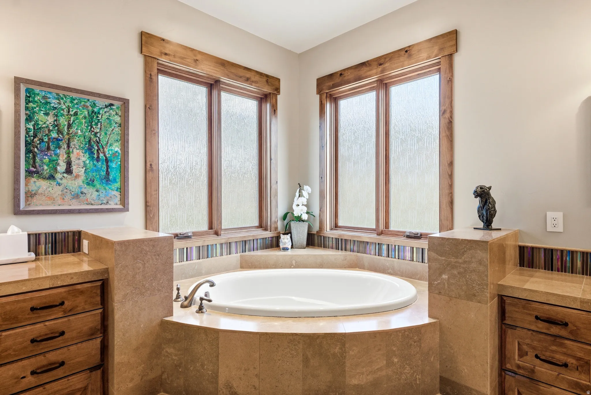Built-in corner soaking tub with deck-mounted faucet and surrounding stone tile
