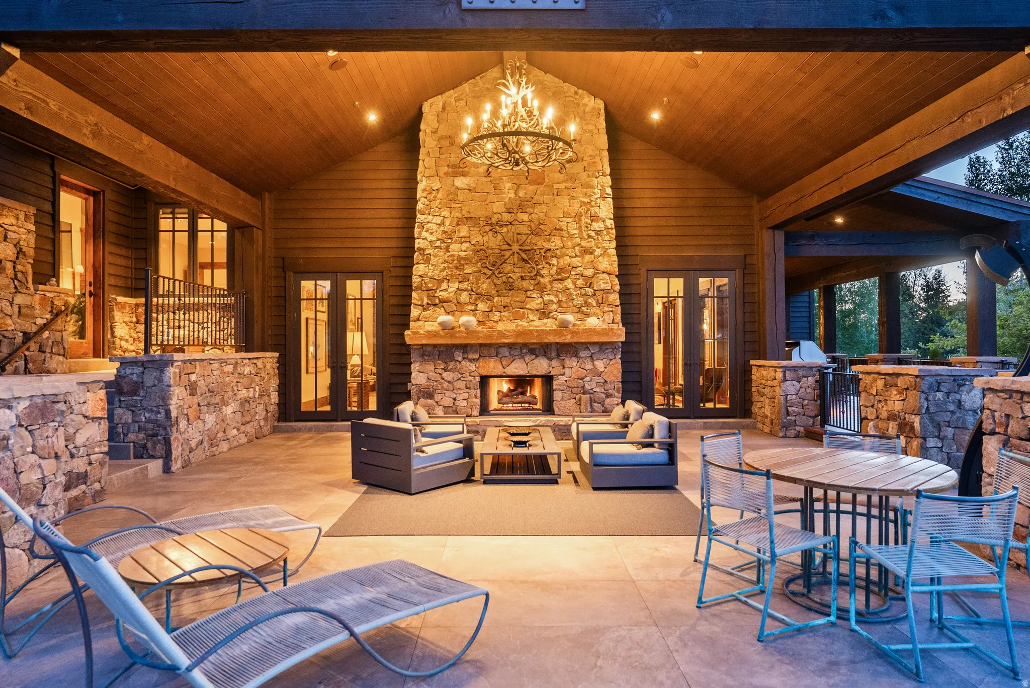 Expansive outdoor living area featuring a stone fireplace, wood-paneled vaulted ceiling, and ample patio space
