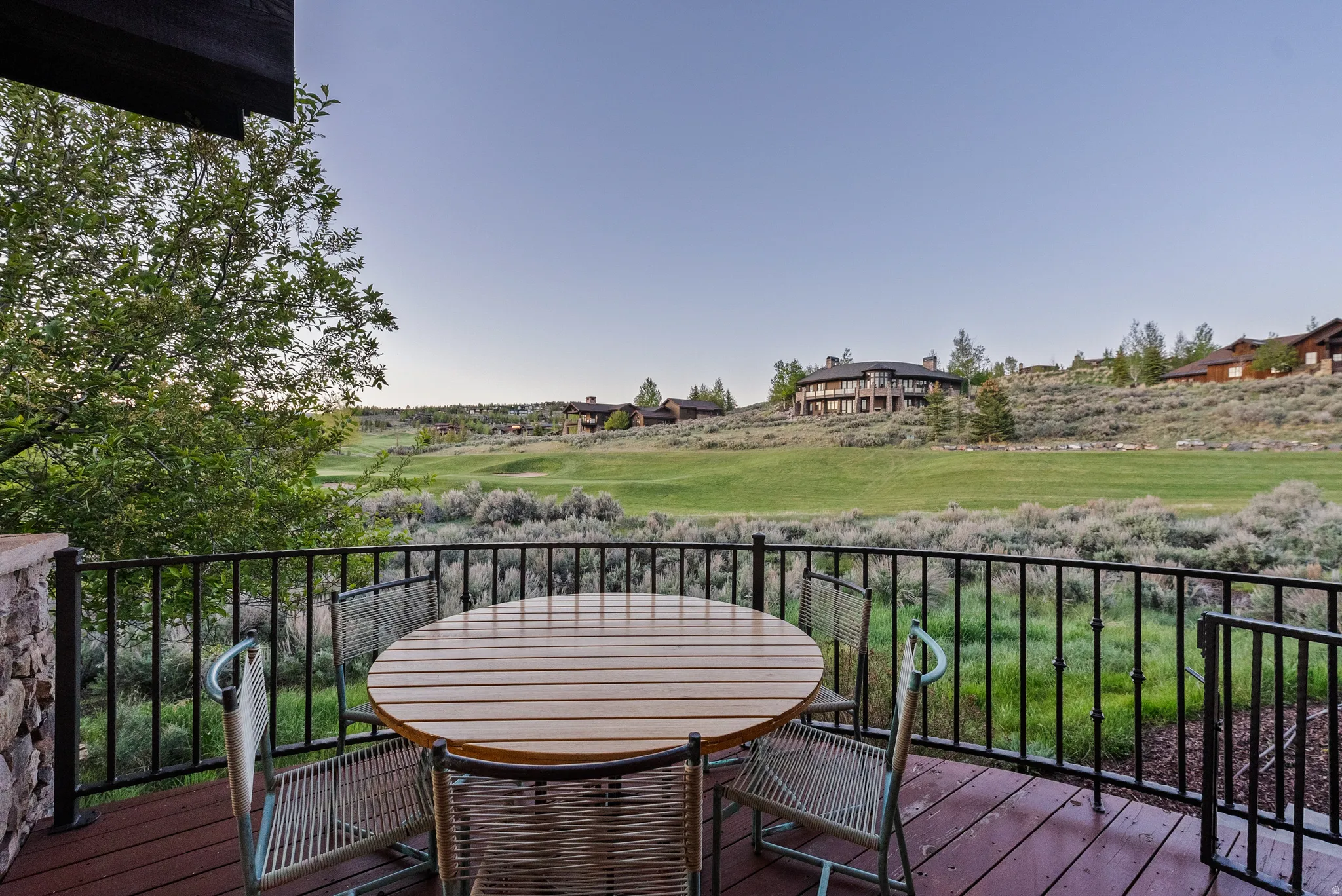 Expansive outdoor deck featuring composite wood flooring, a wrought-iron railing, and stone pillar accents