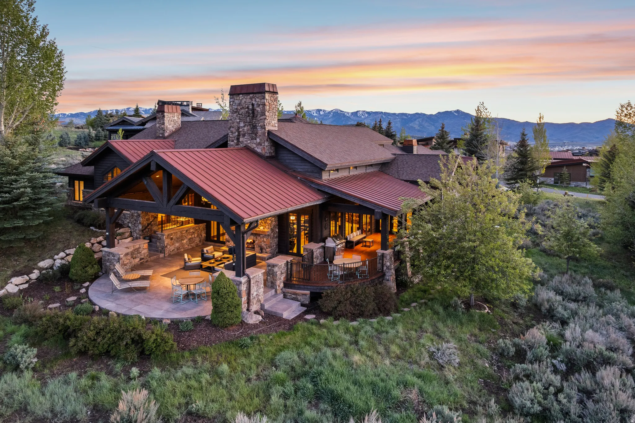 Exterior featuring stone and wood siding, multiple red metal roofs, and a prominent stone chimney