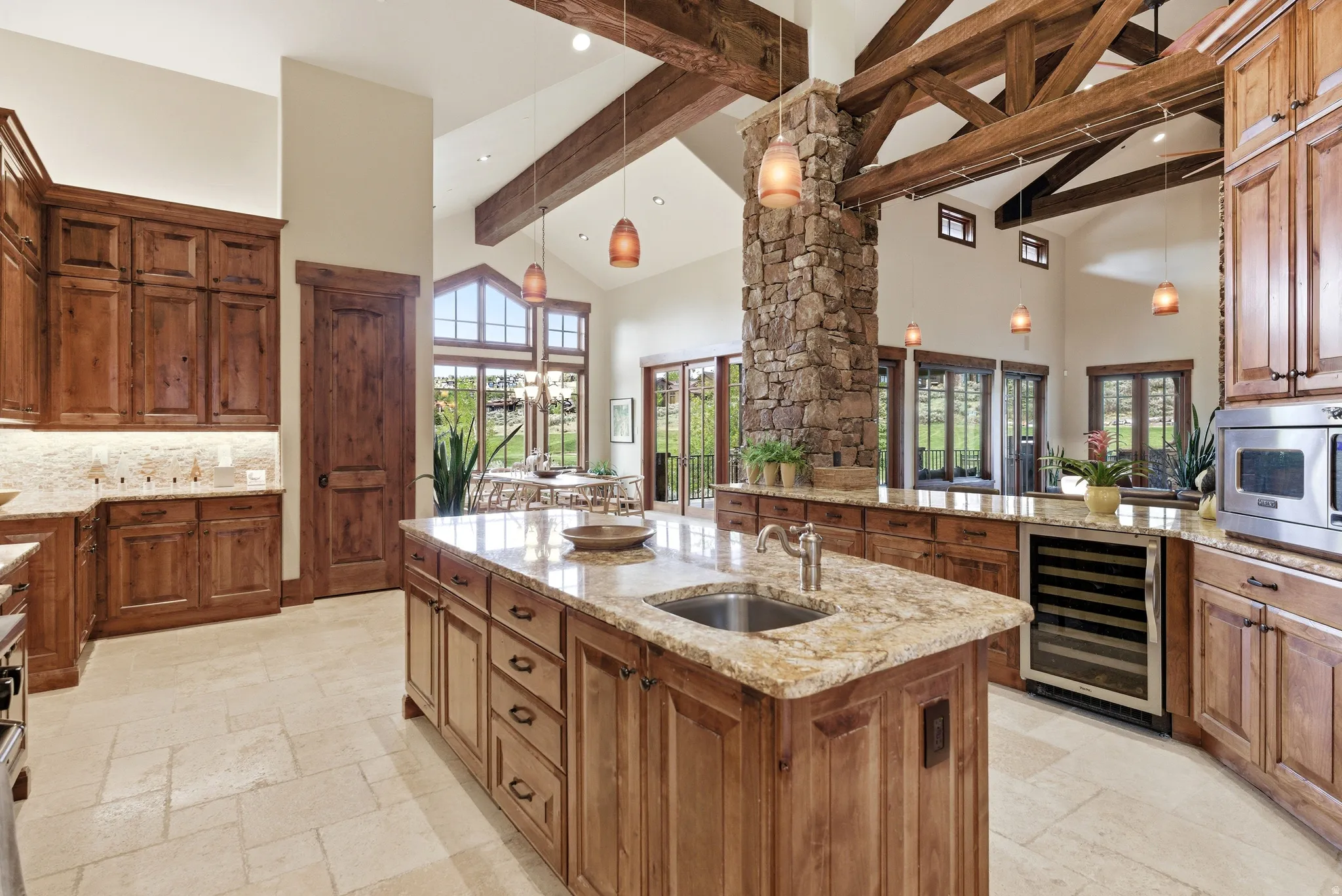 Gourmet kitchen featuring a large central island with an undermount sink, granite countertops, and rich wood cabinetry