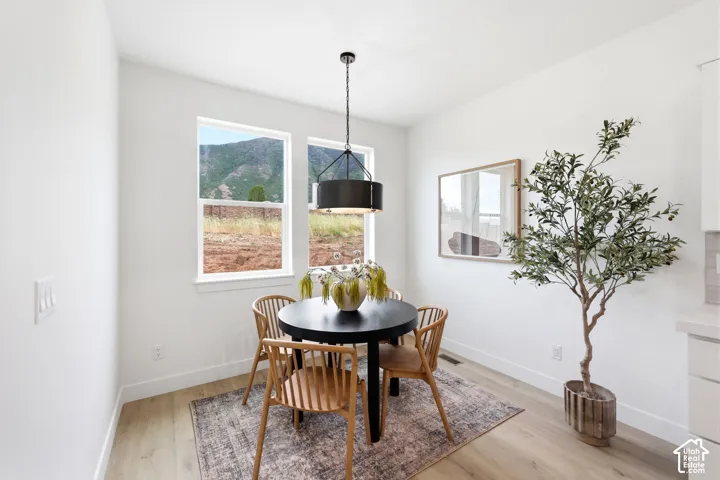Dining area featuring two large windows, wood-finish flooring, and a modern drum pendant light fixture