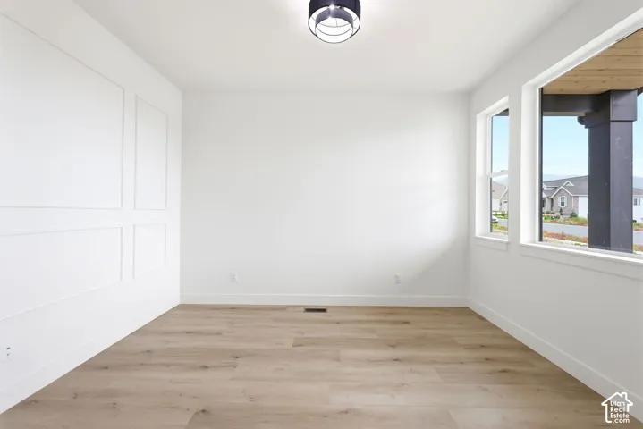 Bright interior space featuring wood-finish flooring, a decorative accent wall with panel molding, and recessed lighting