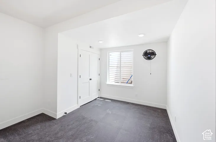 Bright white walls and recessed lighting illuminate this versatile space featuring dark, textured flooring