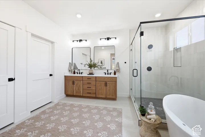 Modern bathroom featuring a dual vanity with wood-finish cabinetry, matte black fixtures, a spacious glass-enclosed shower, a freestanding soaking tub, and plank-style flooring