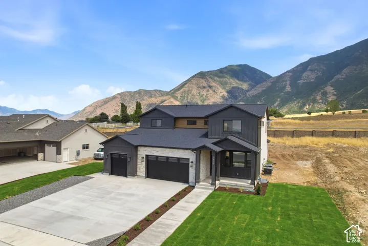 Contemporary home featuring a dual garage, stone and dark siding exterior, and a newly seeded lawn