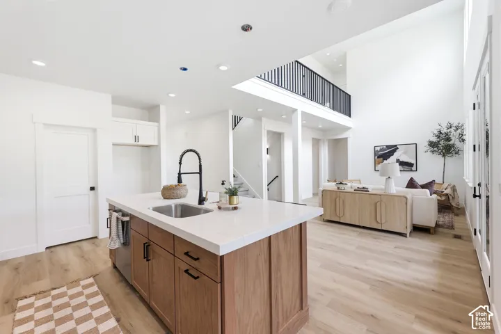 Kitchen island with wood-finish cabinetry, a stainless steel sink, and a black gooseneck faucet