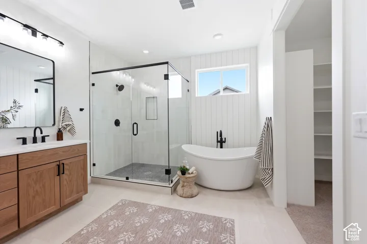 Contemporary bathroom featuring a freestanding soaking tub, glass-enclosed shower, wood-finish vanity with a rectangular sink, and neutral tile flooring