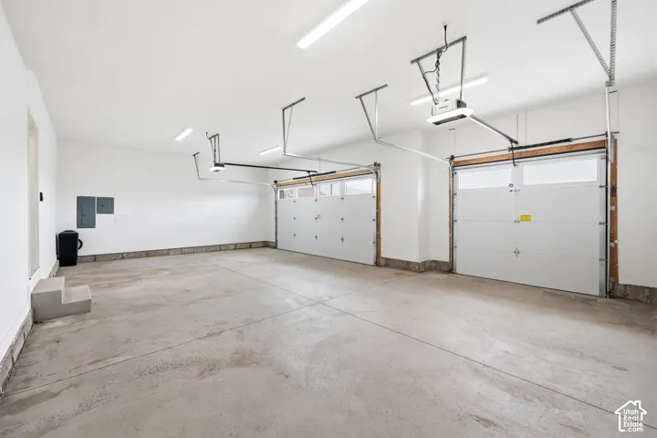 Spacious two-car garage featuring a concrete floor, white painted walls, and overhead fluorescent lighting