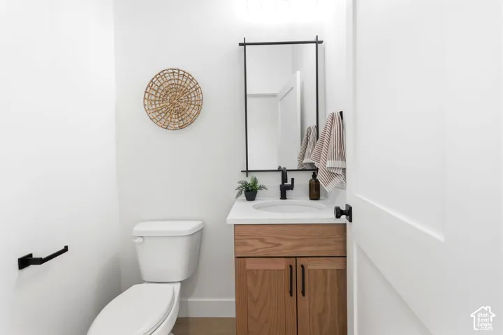 Modern powder room featuring a wood-finish vanity with a white countertop and undermount sink, matte black faucet, and a contemporary wall-mounted mirror with integrated lighting