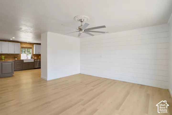 Light wood-finish flooring, white shiplap accent wall, contemporary ceiling fan with decorative medallion, and recessed lighting
