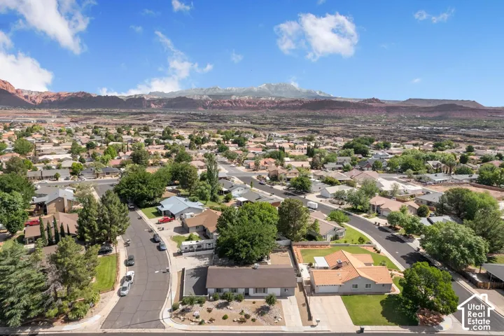 Residential neighborhood with mature trees and paved streets, framed by a mountainous backdrop