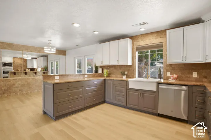 Kitchen featuring wood-finish flooring, two-tone cabinetry, stainless steel appliances, and an apron-front sink