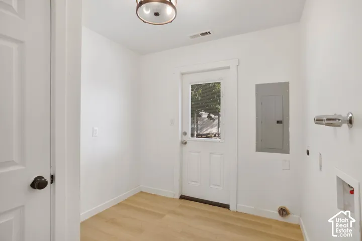 Wood-finish flooring with white baseboards, a utility door with an exterior light, and a surface-mounted ceiling light fixture