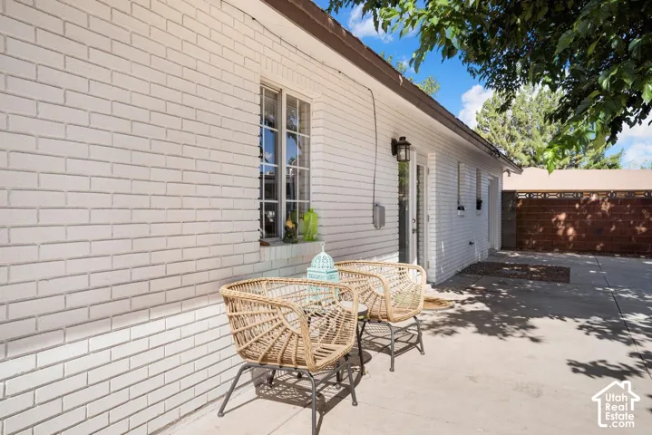 White brick exterior, multi-pane window, exterior lighting fixture, concrete patio, wood-finish privacy fence