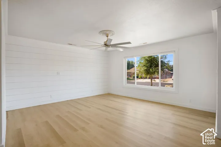 Light wood-finish flooring, white shiplap accent wall, white window trim, and a ceiling fan with decorative medallion