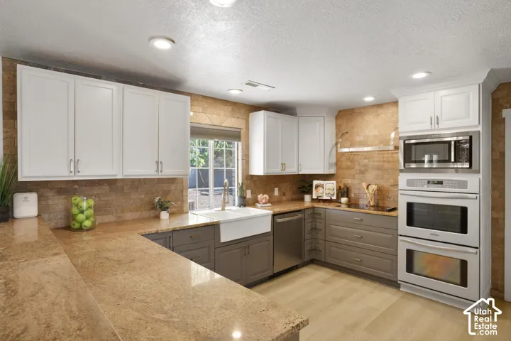 Kitchen with light wood-finish flooring, white upper cabinetry, and gray lower cabinetry