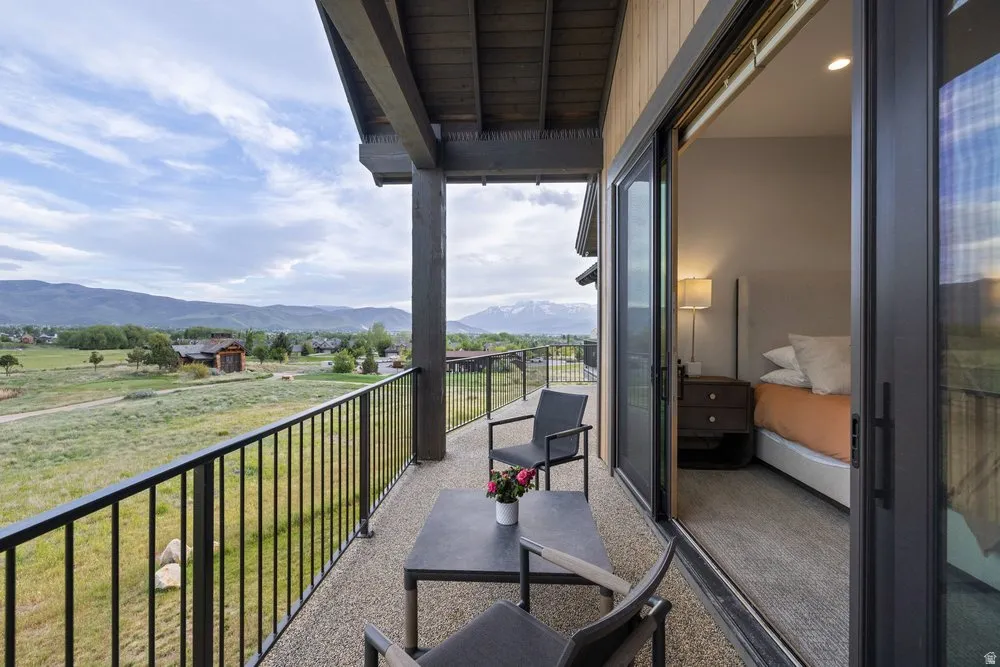 Covered balcony with a stone aggregate surface, featuring an open metal railing, and direct access to an interior room through a sliding glass door