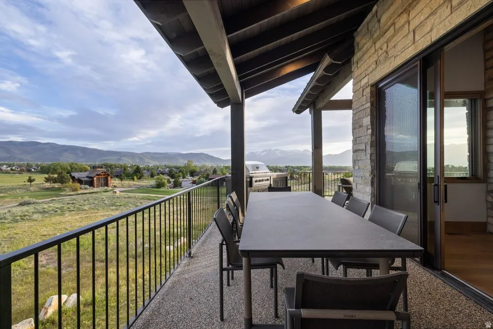 Covered balcony featuring stone-clad exterior walls, exposed wood ceiling beams, and a sliding glass door