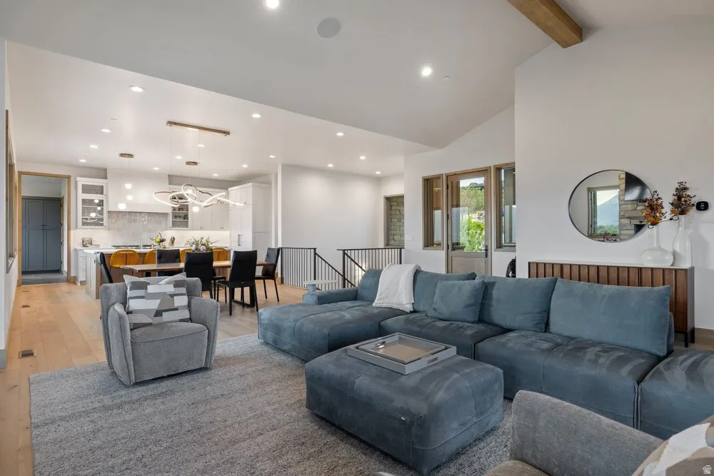 Open-concept living space featuring wood-finish flooring, recessed lighting, and a vaulted ceiling with exposed beams