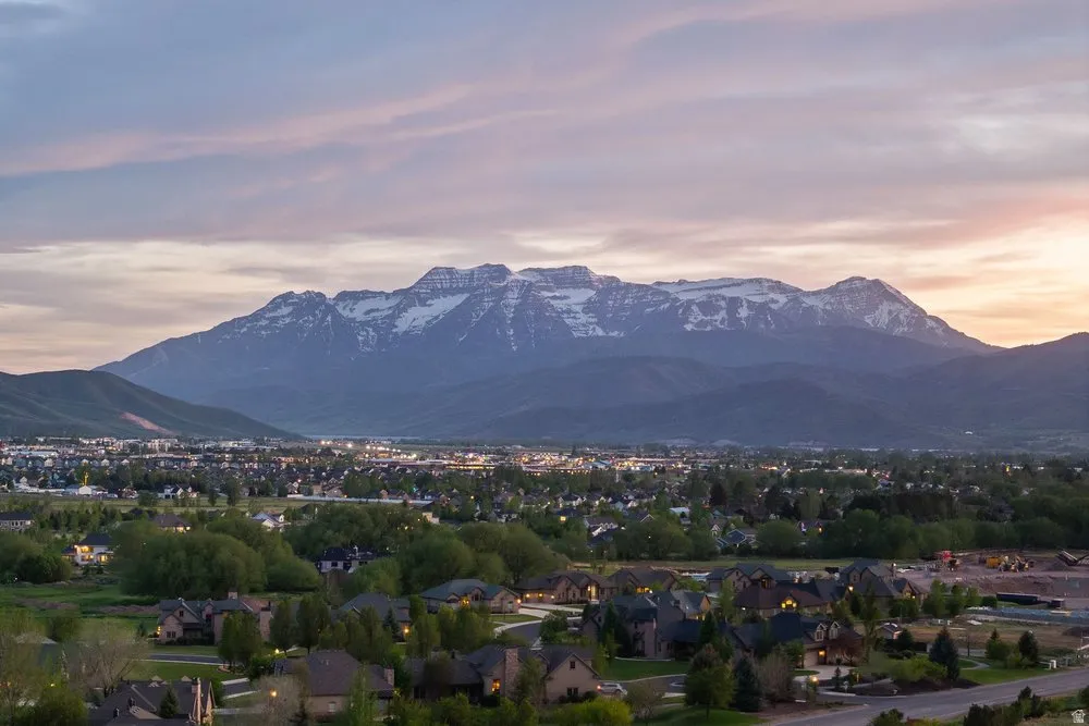 Expansive mountain range backdrop for a residential area featuring diverse rooftops and verdant trees