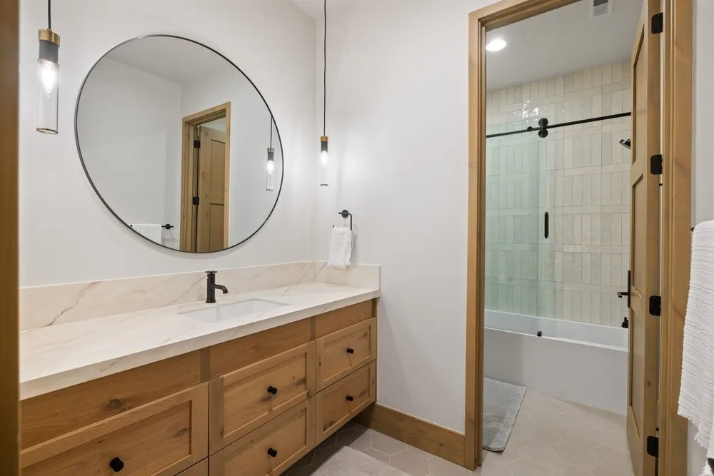 Bathroom featuring a wood-finish vanity with a light-toned countertop, an undermount sink, and a black faucet