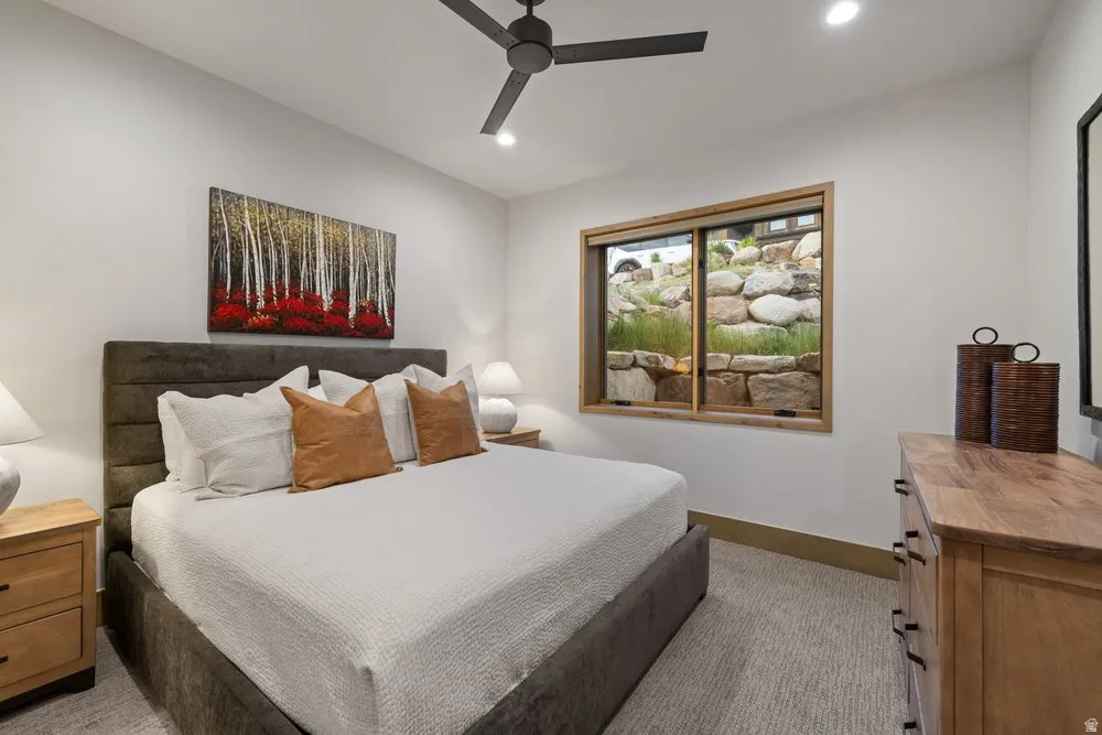 Recessed lighting illuminates a neutral-toned room featuring light-colored carpet flooring and a window with a wood frame