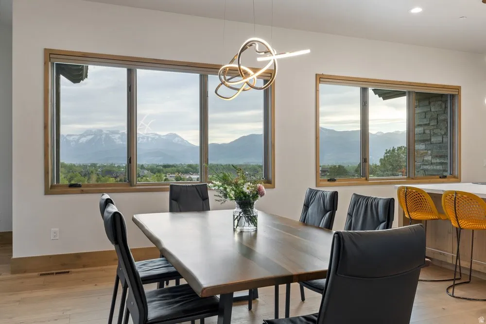 Dining area featuring expansive windows with wood-finish trim, a contemporary linear chandelier, and wood-finish flooring