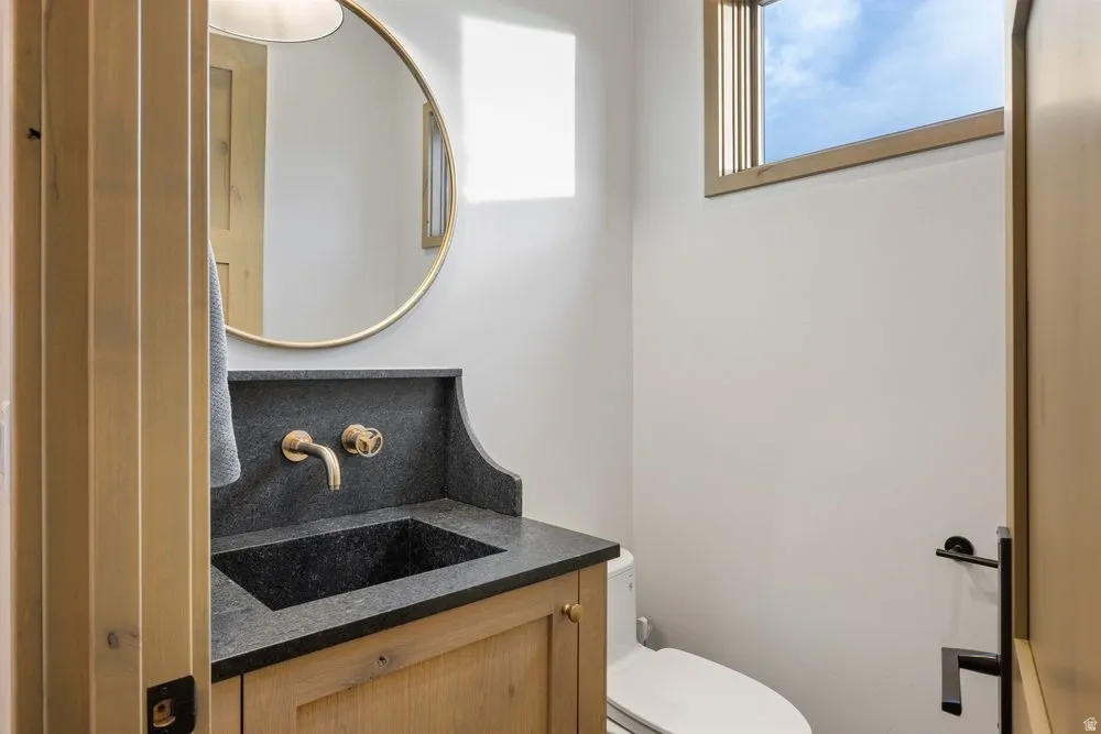 Powder room featuring a custom wood vanity with a dark stone countertop and integrated sink