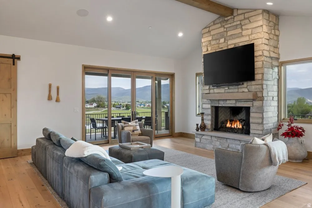 Expansive living area featuring a stone fireplace with a raised hearth, wood-finish flooring, and a barn door