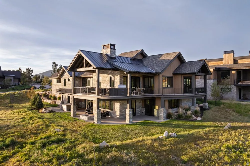 Multi-level exterior featuring stone and horizontal siding, a metal roof, and an expansive upper balcony with glass railings
