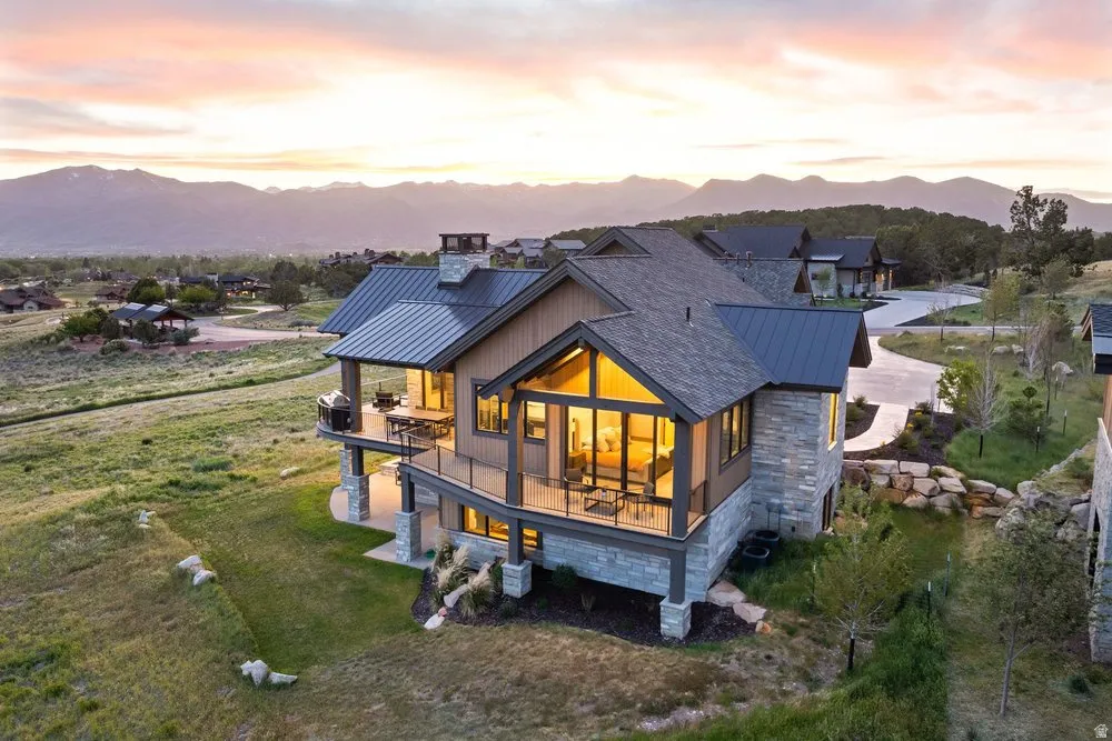 Multi-level residence featuring a stone and wood-panel exterior, multiple balconies, a covered patio, and extensive windowing