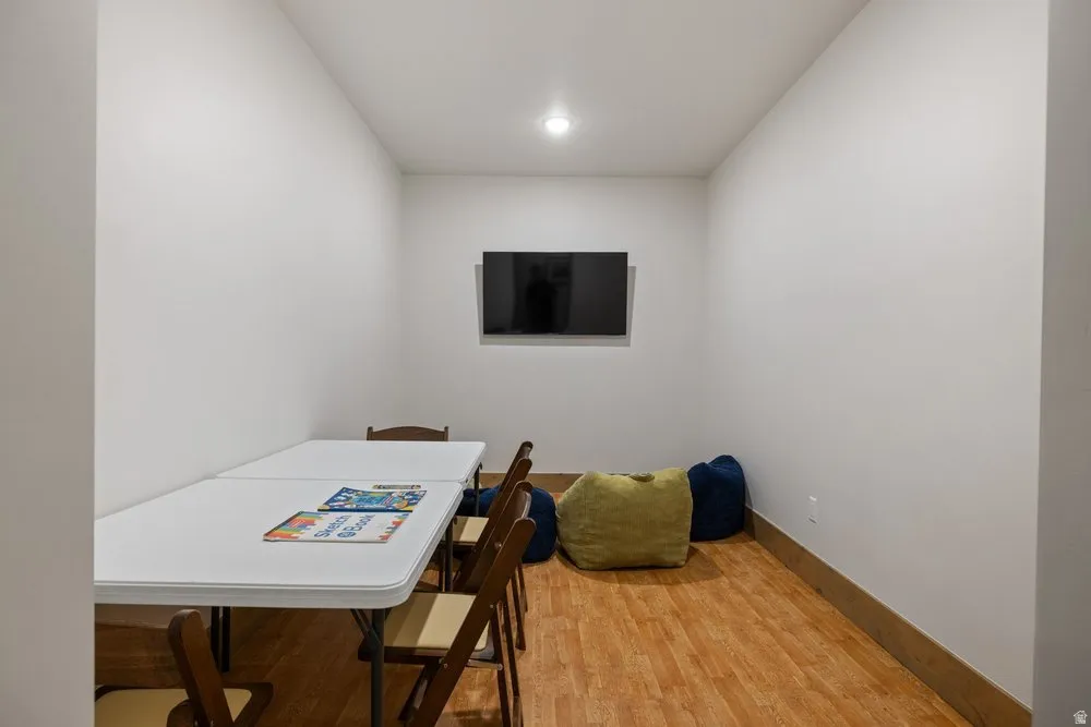 Compact room featuring a wall-mounted television, recessed lighting, wood-finish flooring, and light-toned walls