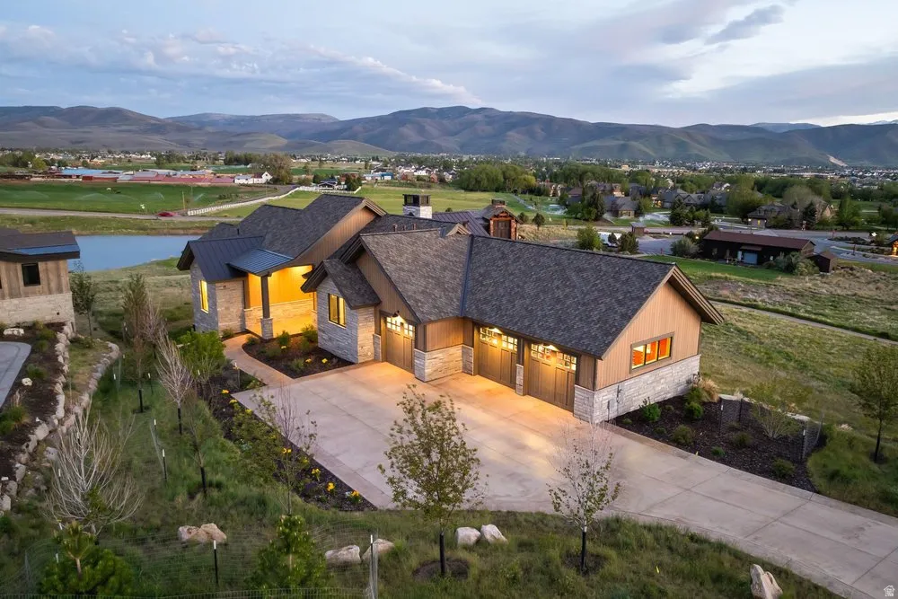 Contemporary residence featuring stone and wood siding, a multi-car garage, and a concrete driveway