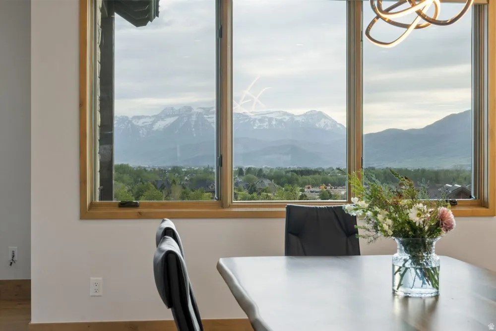 Large picture windows with natural wood frames showcasing distant mountains and a verdant landscape