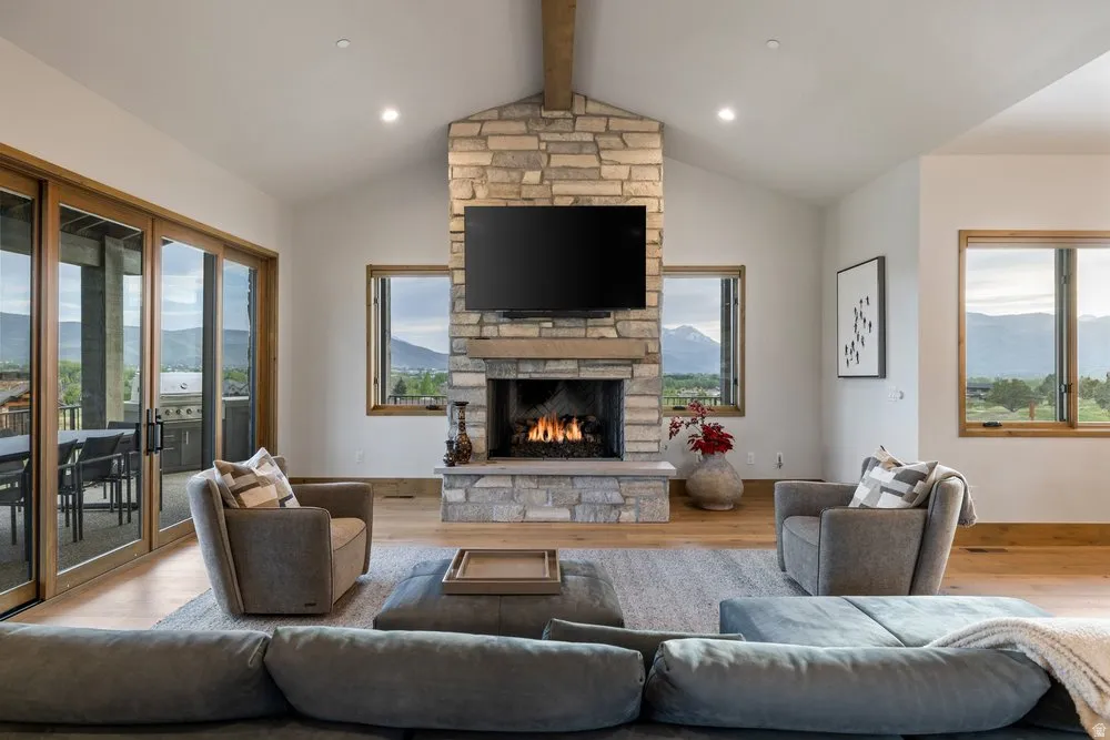 Vaulted ceilings enhance this living space featuring a stone-clad fireplace and wood-finish flooring