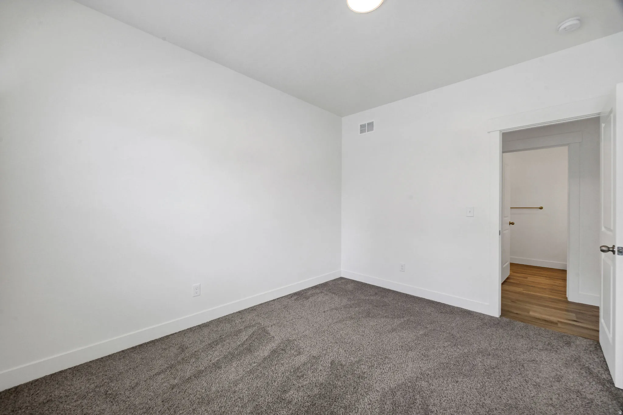 Spacious room featuring neutral carpeting and white baseboards