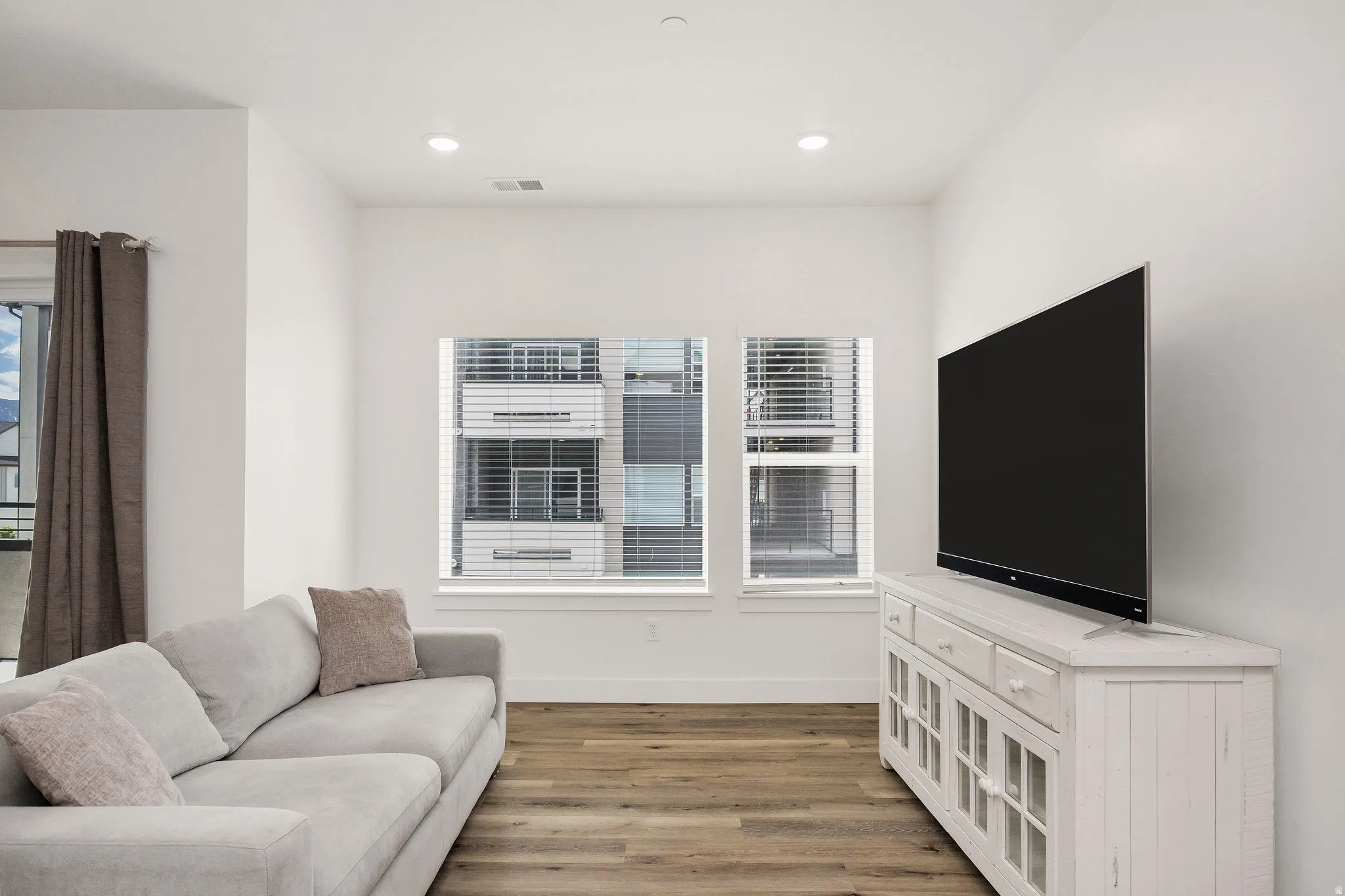 Living area featuring wood-finish flooring, recessed lighting, and white walls