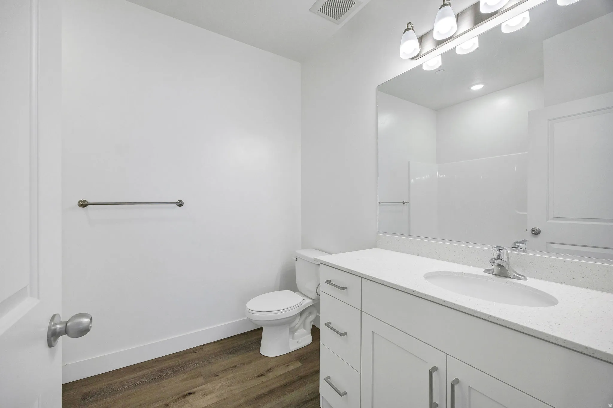 Contemporary bathroom featuring a white vanity with integrated sink, a large mirror, and a modern light fixture