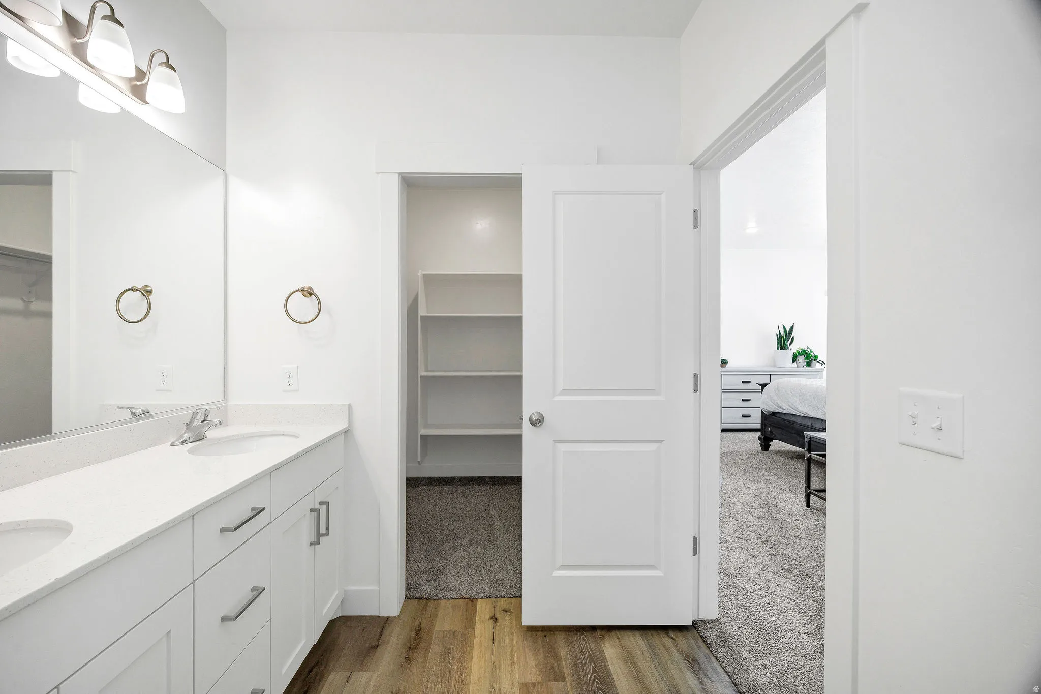 Bathroom vanity with dual undermount sinks, white cabinetry, and a light-toned countertop