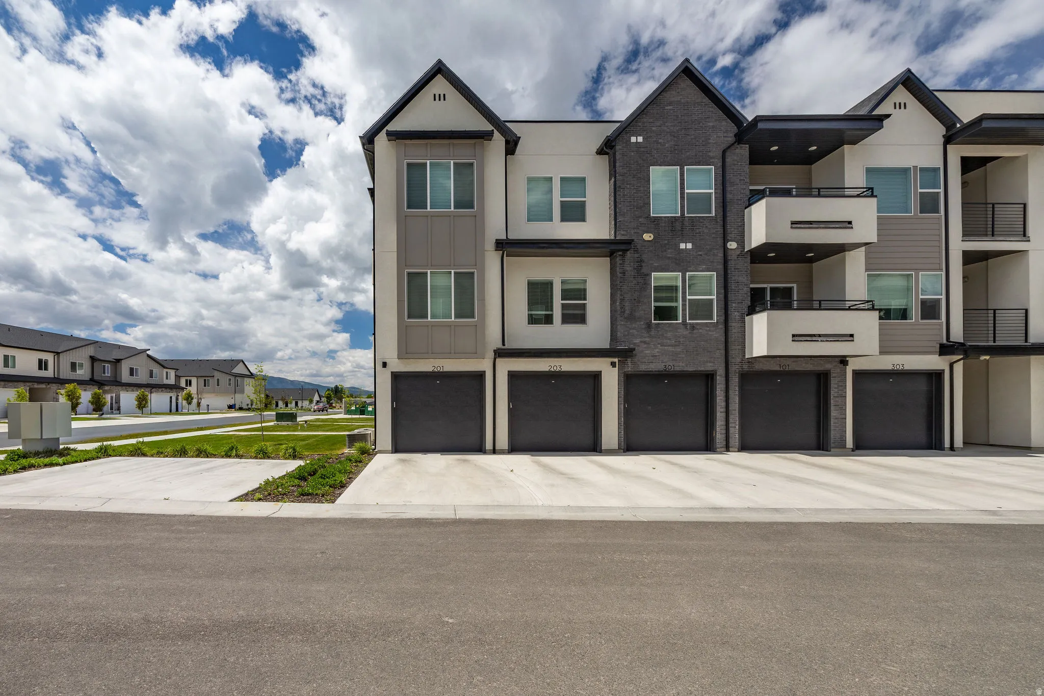Contemporary townhome-style residences featuring multi-level facades with varied siding, private balconies, and integrated garages